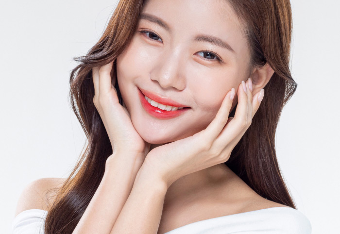 두손으로 턱을 감싸면서 치아가 보일정도로 밝게 웃고 있는 여성의 모습